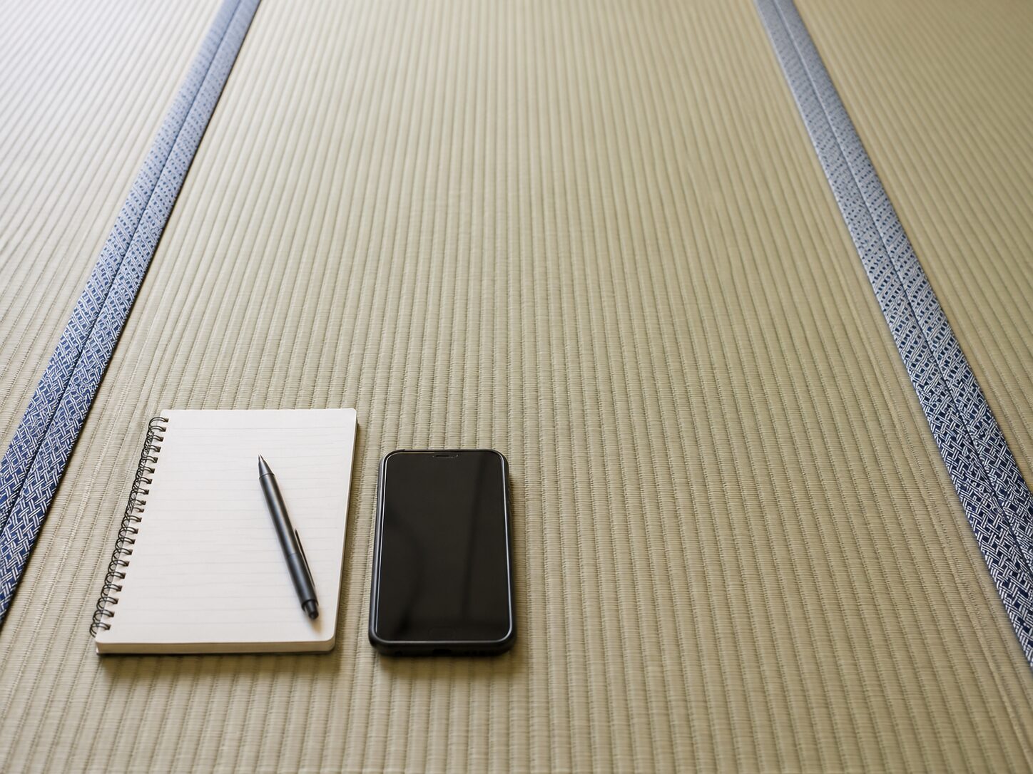 長辺側に畳縁がある畳の状態をノートとスマートフォンで確認する様子